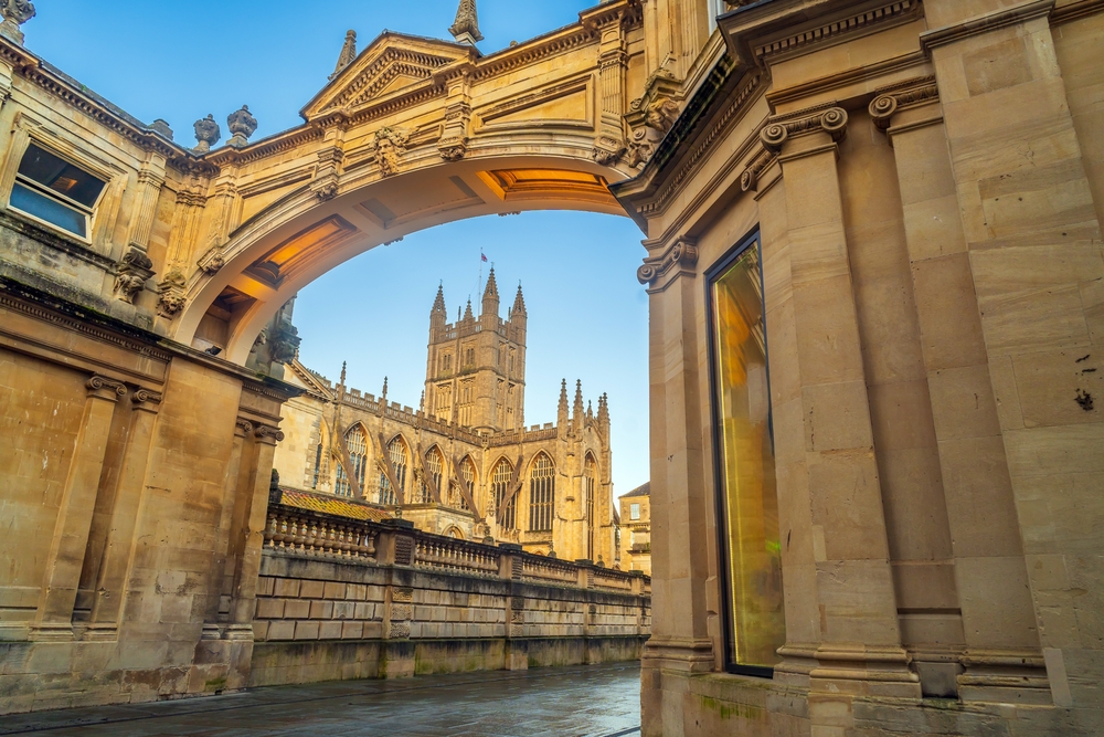 A képen a Bathi apátsági templom (Bath Abbey) látható az angliai Bath városában, amelyet egy kőív alól fotóztak.  - Z(s)eppelin utazás